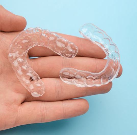 Two clear aligners resting on person’s hand