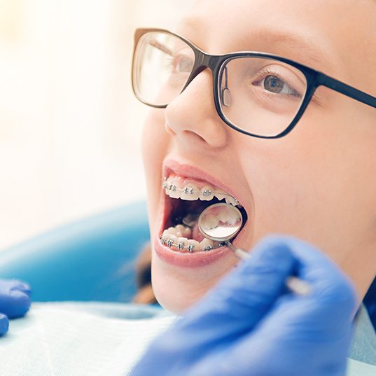 A dentist checking a young girl’s braces