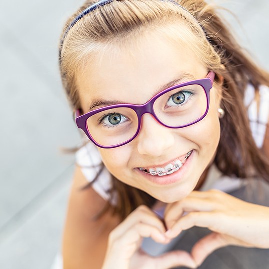 A young girl smiling with braces while looking up