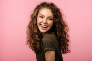 Girl smiling with braces on pink background