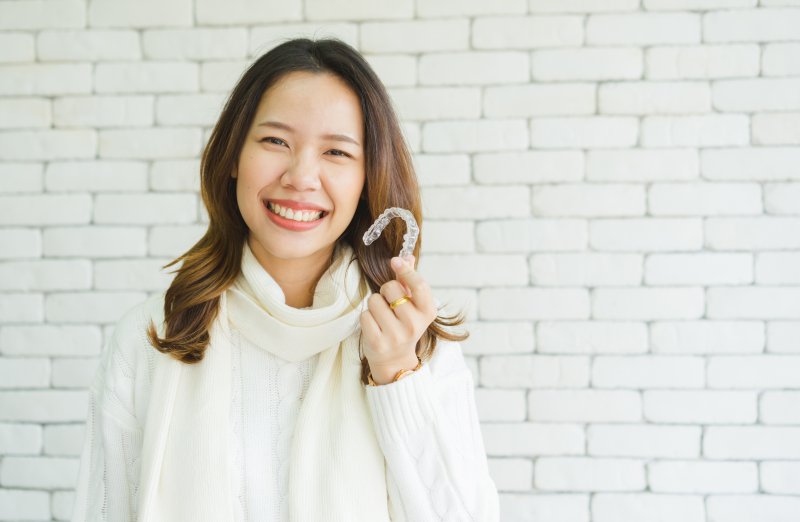 smiling woman in sweater holding Invisalign