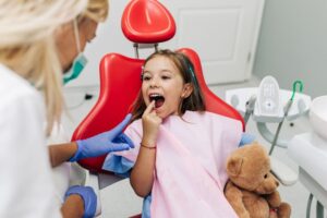 Little girl pointing at her teeth, talking to dental team member