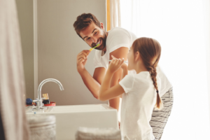 a parent and their child brushing their teeth